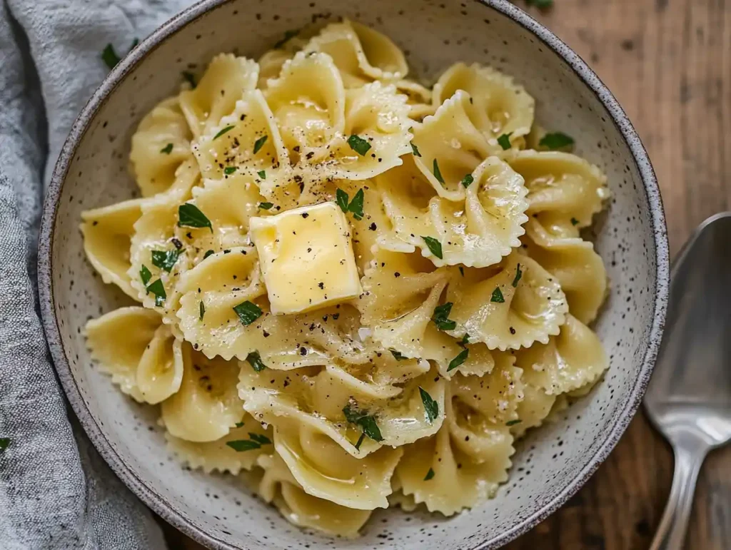 A bowl of cooked pastina served with butter and herbs.